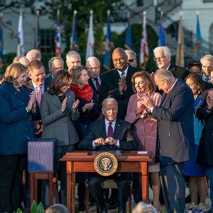 President Biden signs the Infrastructure Investment and Jobs Act, surrounded by congressional supporters