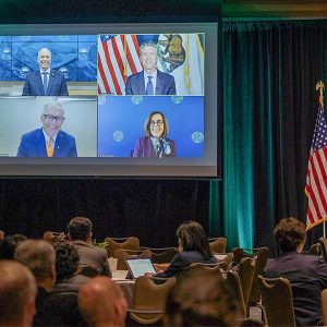 Attendees at the Cascadia Innovation Corridor Conference watched, clockwise on screen, Premier John Horgan and governors Newsom, Brown and Inslee.