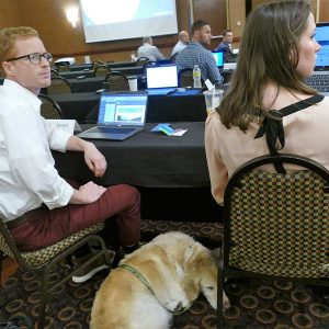 Morgan, a golden retriever catching some Zs between Puget Sound Energy's Greg Macdonald and Catherine Whitten, her owner, was among the attendees for both Markets+ sessions.