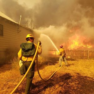 Firefighters try to protect a home in Greenville, Calif., a community destroyed by the Dixie Fire in August.