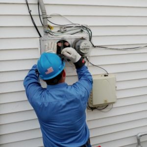 A Con Edison worker connects an adapter that uses the residential electric meter socket as a point of interconnection for solar power.