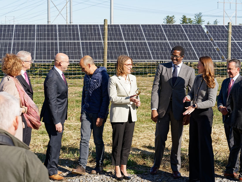 NYSERDA President Doreen Harris, center, wields a utility-scale pair of scissors at a ribbon-cutting for a milestone distributed solar project in New York on Oct. 17.