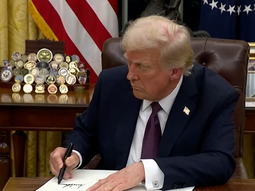 President Donald Trump signs executive orders in the Oval Office on Jan. 20.